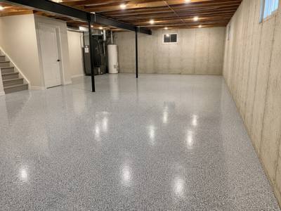 Grey flake floor across an open basement with poured concrete walls